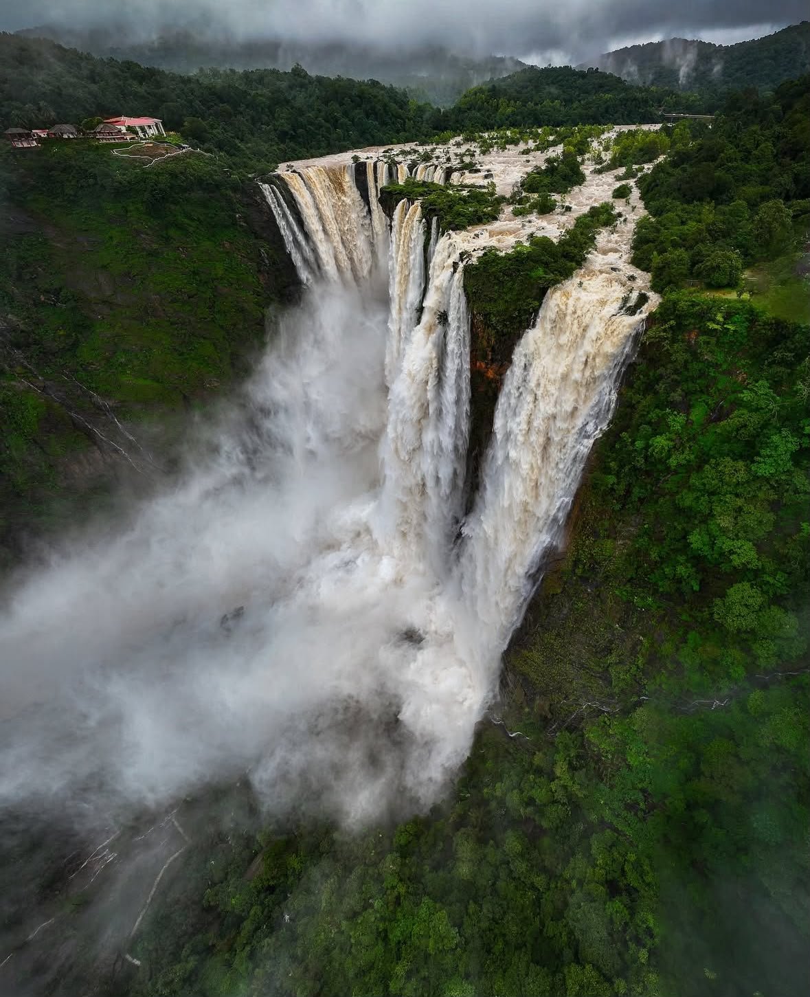Jog Falls Karnataka — breathtaking aerial view of dramatic four-tiered waterfall in full monsoon flow surrounded by green hills